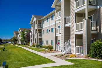 A row of apartment buildings with balconies and flower pots on the steps.